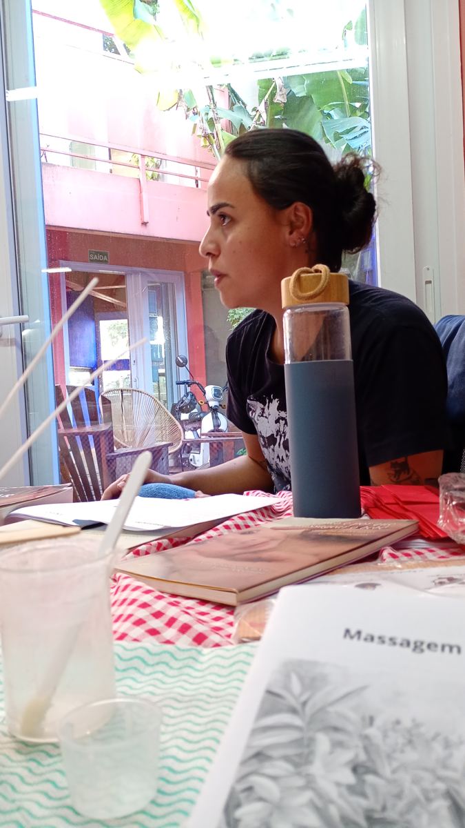 Participante à mesa da oficina Alma Acesa durante a vivência de vela de massagem