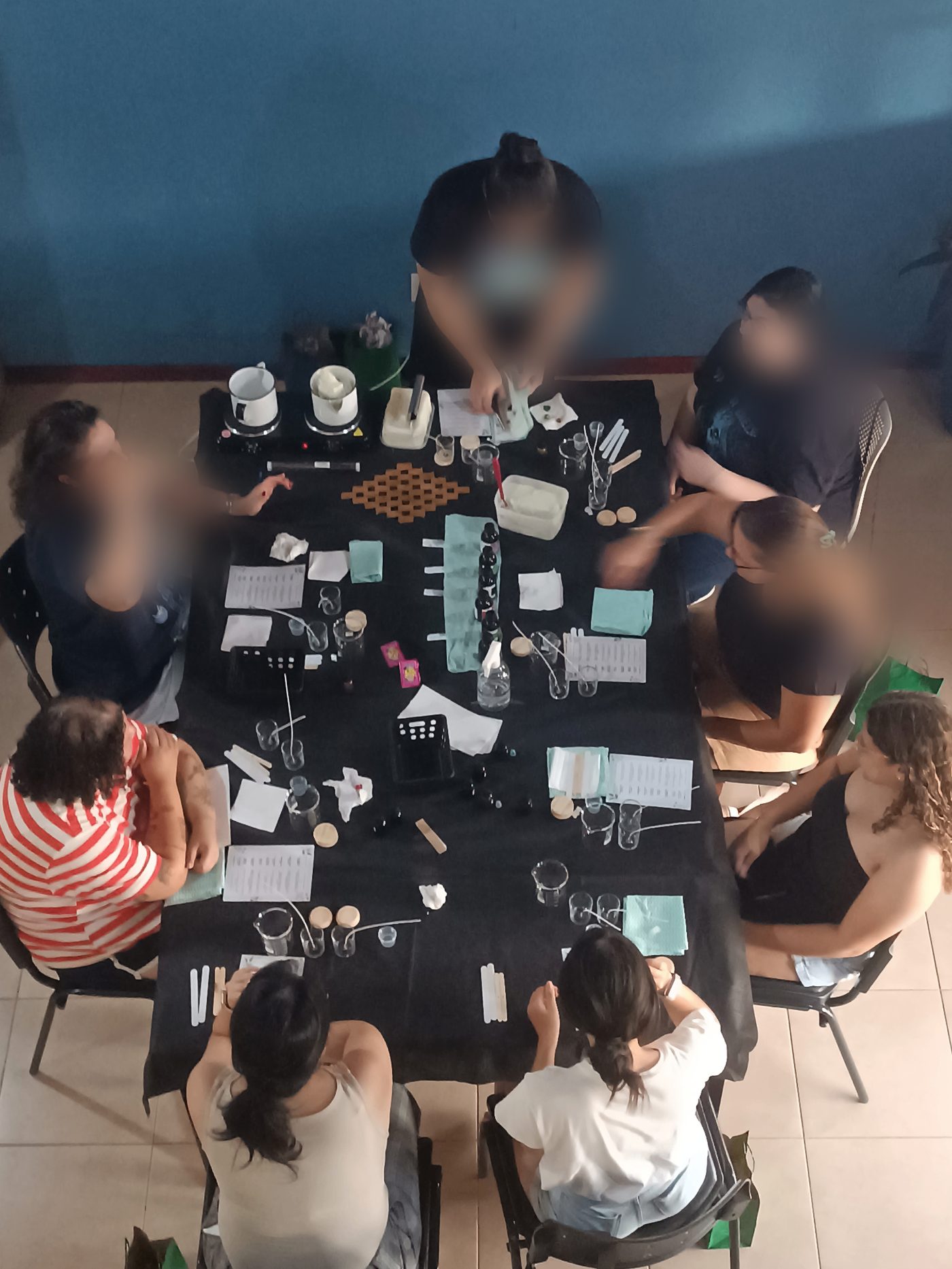 Vista superior da mesa da oficina Essência, com kits para produção de velas artesanais, essências e materiais individuais