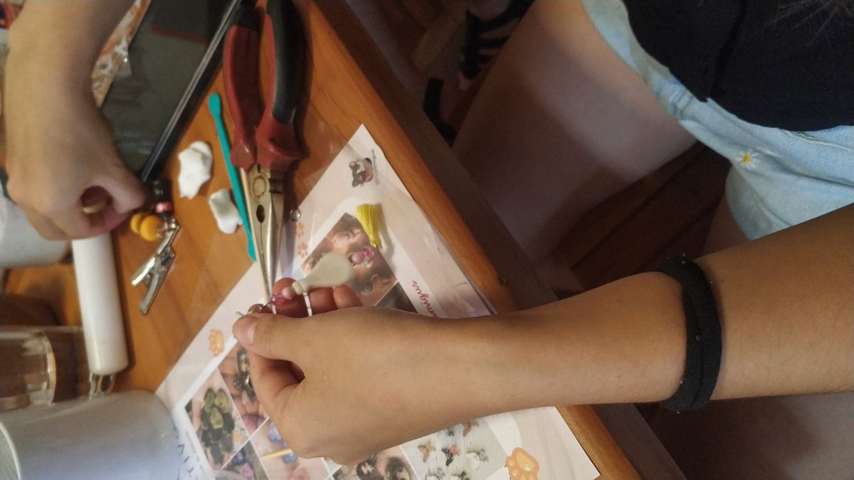 Participante modelando chaveiros de biscuit sobre a mesa da oficina Formas de Afeto