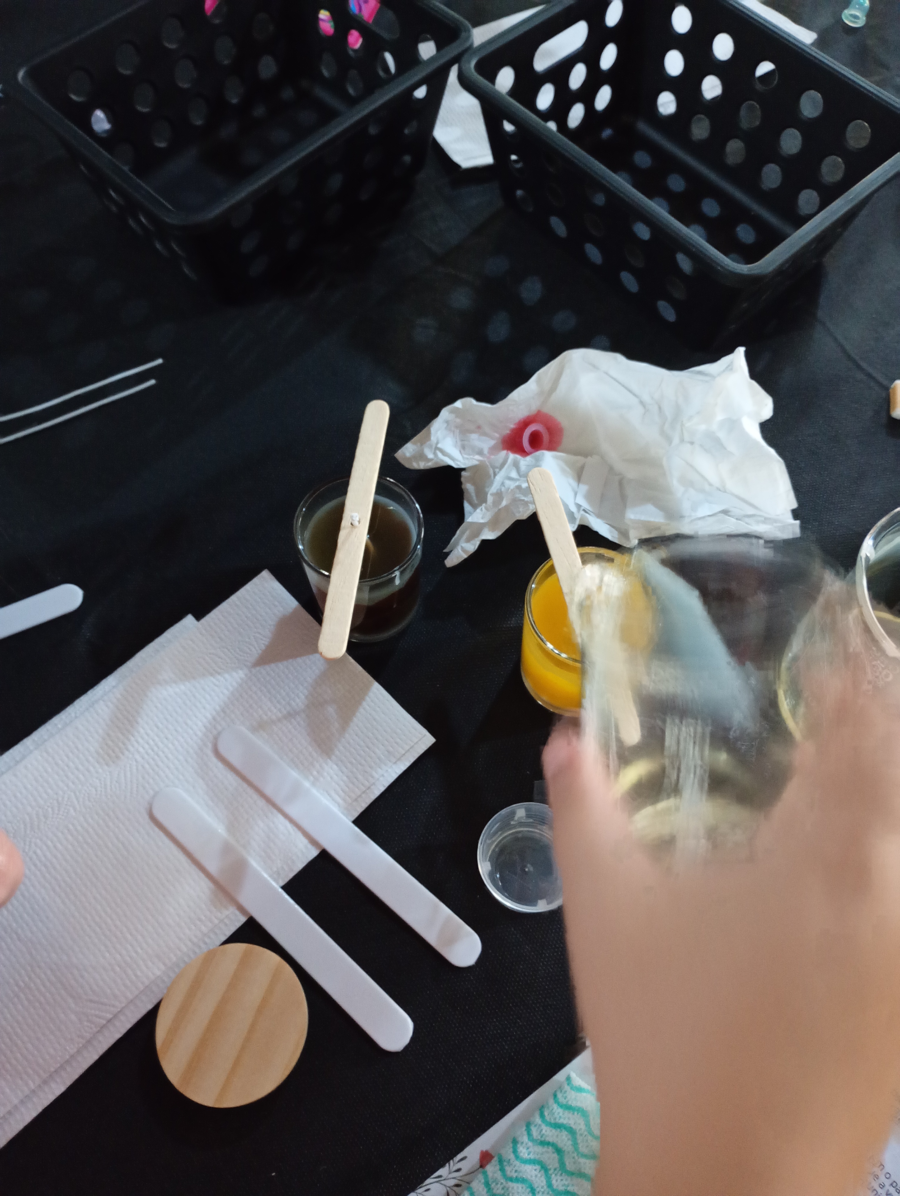 Vista de cima de mesa de oficina criativa com novelos coloridos de lã, agulhas de crochê, xícaras de chá e pequenos amigurumis sendo criados pelas participantes