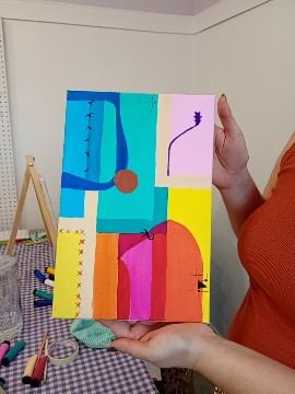 Participante segurando a tela colorida que pintou na oficina Pincelando