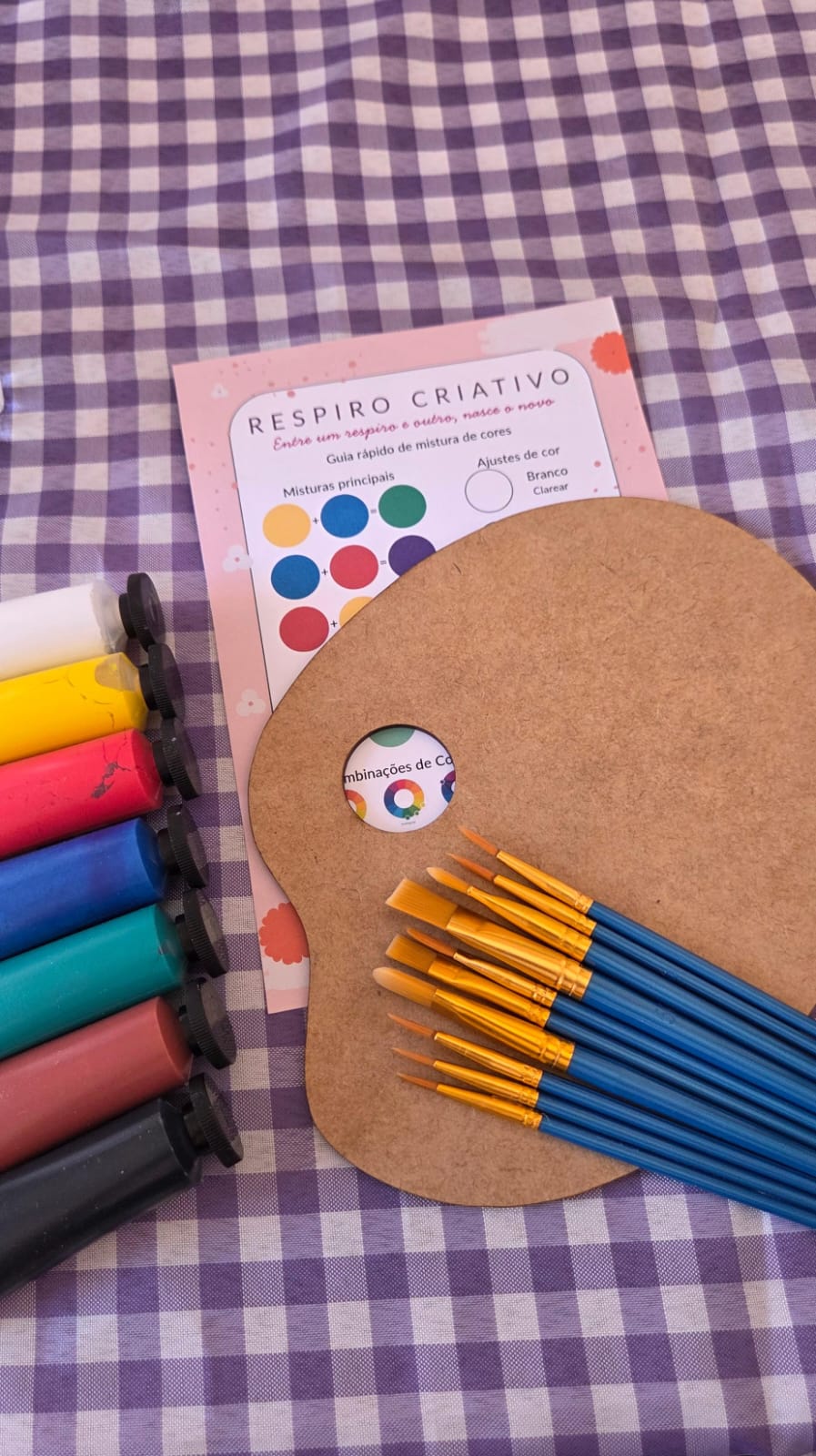Mesa de aula de artes manuais preparada com tintas, pincéis, paletas e materiais organizados para uma aula presencial em São Carlos