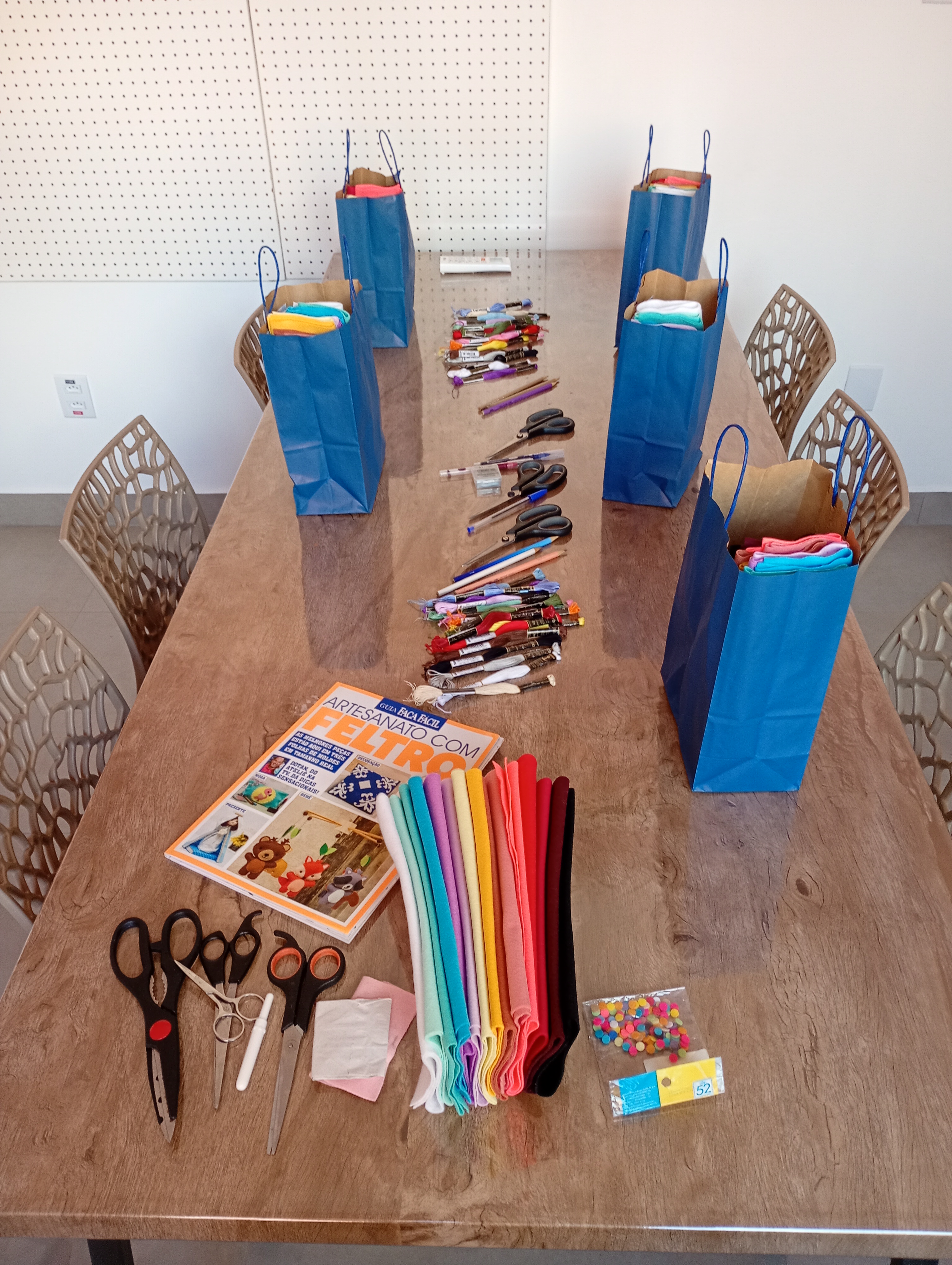 Mesa preparada com kits individuais azuis e materiais organizados para a oficina Unindo os Pontos